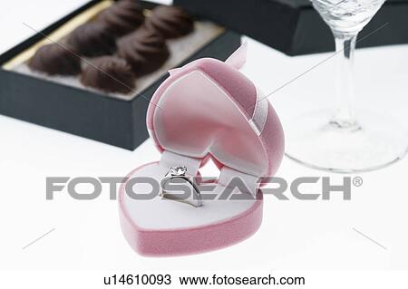 Diamond ring in a heart shaped box with a box of chocolates and a wineglass View Large Photo Image Stock Image - Diamond ring in a heart shaped box with a box of chocolates and a wineglass. Fotosearch