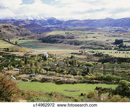 Stock Image - Farmland under mountain range. New Zealand. Fotosearch