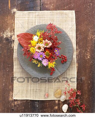 Stock Image - Flowers on a plate on a wooden table. Fotosearch