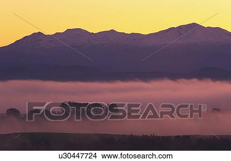 Picture - Fog over landscape at sunset. Fotosearch