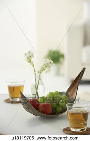Stock Photograph - Fruit in a leaf bowl on a table with tea. Fotosearch