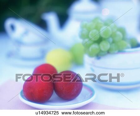 Stock Photography - Fruit on table outdoors with tea cups and teapot. Fotosearch
