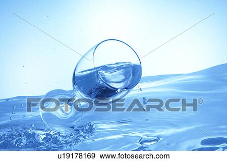 Stock Photo - Glass of water falling on water surface, blue background. Fotosearch