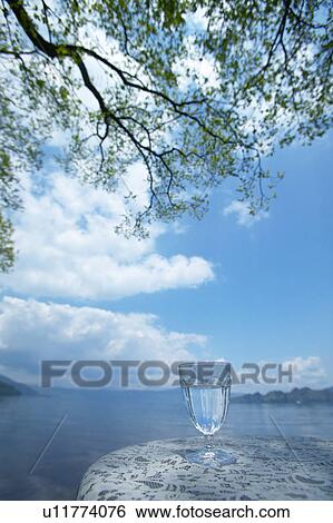 Stock Photograph - Glass of water on a table by a lake, Towada, Aomori Prefecture, Japan. Fotosearch