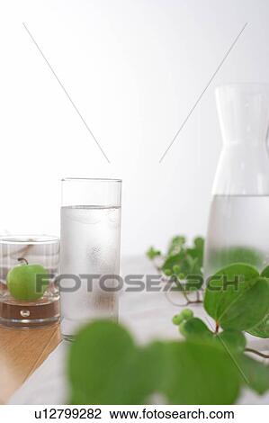 Stock Image - Glass of water with an apple and plant. Fotosearch