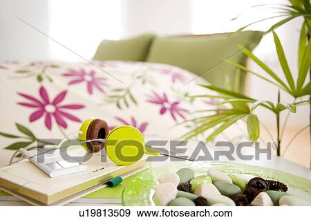 Stock Photo - Green headphones and notebook in a bedroom. Fotosearch