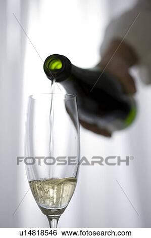 Stock Photograph - Hand pouring champagne into champagne flute. Fotosearch