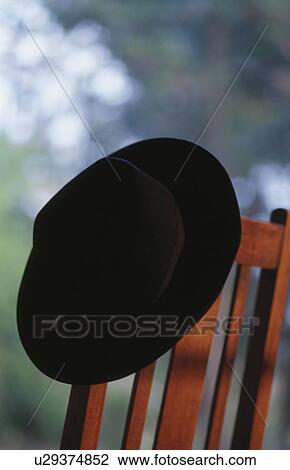 Stock Image - Hat hanging on wooden chair. Fotosearch