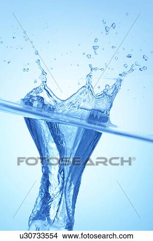 Picture - Ice cube dropped in water, close up, blue background. Fotosearch