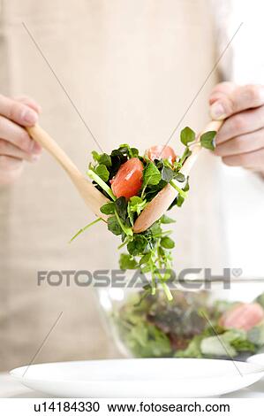 Stock Image - Man serving salad. Fotosearch