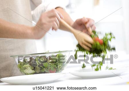 Stock Image - Man serving salad. Fotosearch