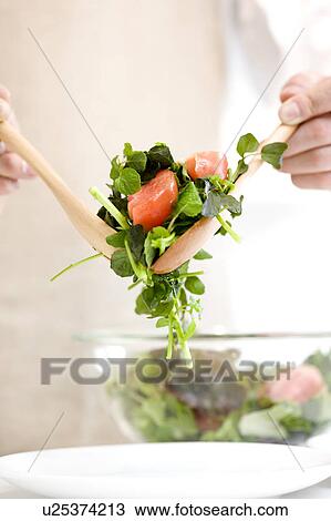 Stock Image - Man serving salad. Fotosearch