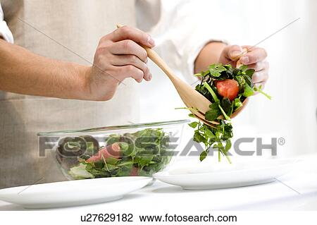 Stock Image - Man serving salad. Fotosearch
