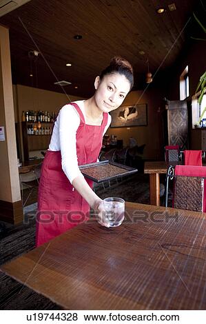 Stock Photo - Mid Adult Woman Bringing Glass of Water at Table. Fotosearch