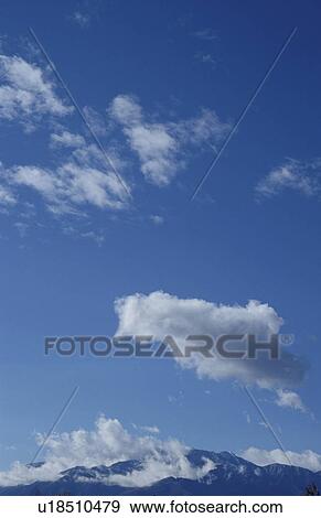 Stock Photo - Mt. Fuji under clouds in a blue sky, Yamanashi Prefecture, Japan. Fotosearch