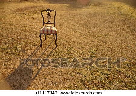 Old-fashioned chair in field casting shadow on grass View Large Photo Image Stock Photo - Old-fashioned chair in field casting shadow on grass. Fotosearch