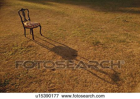 Old-fashioned chair in field casting shadow on grass View Large Photo Image Stock Photo - Old-fashioned chair in field casting shadow on grass. Fotosearch