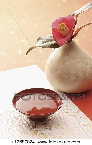 Picture - Pink camellia next to a cup of saki. Fotosearch