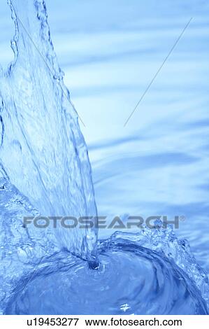 Stock Photo - Pouring water, close up, blue background. Fotosearch