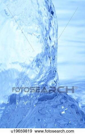 Stock Photo - Pouring water, close up, blue background. Fotosearch