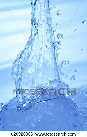 Stock Photograph - Pouring water, close up, blue background. Fotosearch