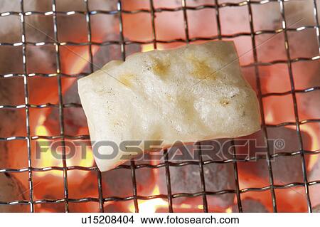 Picture - Rice cake cooking on charcoal fire. Fotosearch