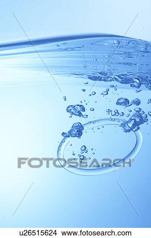 Picture - Ring dropped in water, blue background. Fotosearch