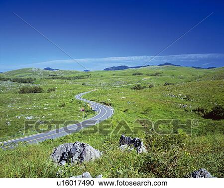 Stock Image - Road winding through fields, Akiyoshidai, Yamaguchi Prefecture, Japan. Fotosearch