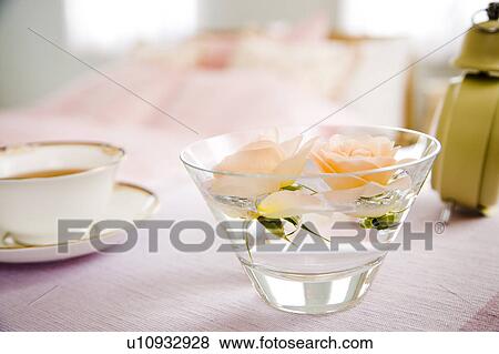 Stock Photo - Roses in a bowl of water and a cup of tea on a bed. Fotosearch