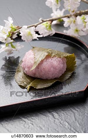 Stock Image - Sakuramochi on a tray with cherry blossom branch. Fotosearch