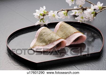Stock Image - Sakuramochi on a tray with cherry blossom branch. Fotosearch