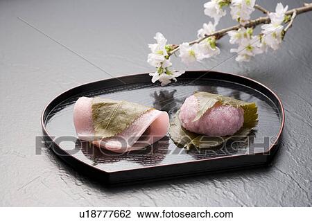 Stock Image - Sakuramochi on a tray with cherry blossom branch. Fotosearch
