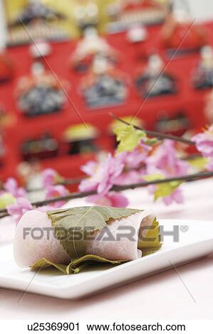 Stock Image - Sakuramochi with peach flowers and Japanese dolls. Fotosearch