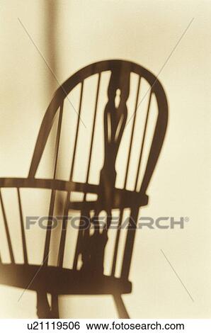 Stock Photograph - Shadow of a chair cast on white wall. Fotosearch
