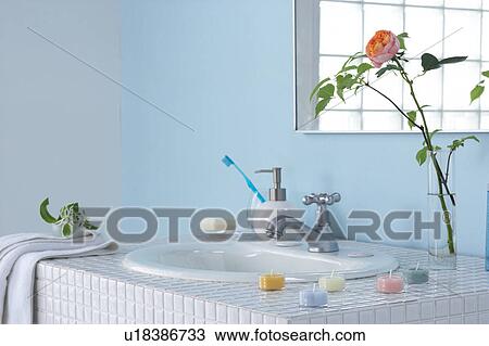 Stock Image - Sink in bathroom with rose in vase and bars of soap. Fotosearch