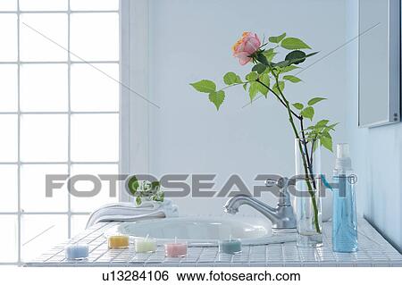Stock Photograph - Sink in bathroom with rose in vase and bars of soap. Fotosearch