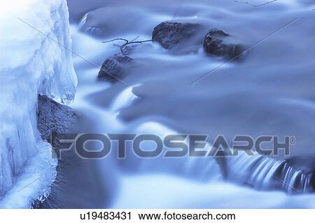 Stock Image - Snow on rocks in river. Fotosearch