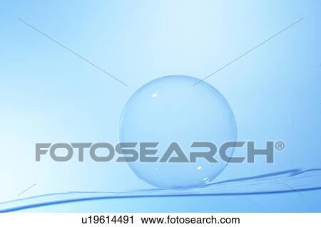 Stock Image - Soap bubble on water surface, blue background. Fotosearch