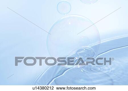 Stock Image - Soap bubbles on water surface, blue background. Fotosearch