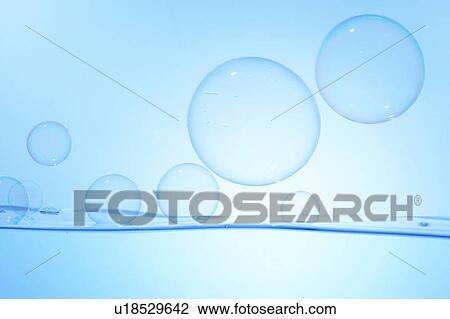 Stock Image - Soap bubbles on water surface, blue background. Fotosearch
