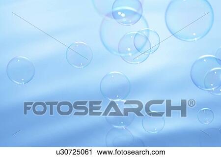 Stock Image - Soap bubbles over water surface, blue background. Fotosearch