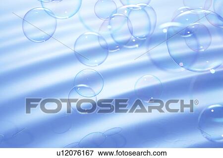 Stock Photo - Soap bubbles over water surface, blue background. Fotosearch