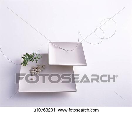 Stock Image - Square white plates, pebbles and a spiral leaf. Fotosearch