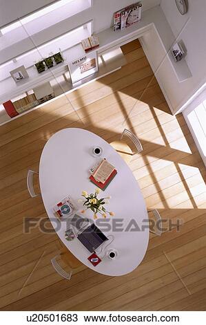Stock Image - Table in living room with coffee cup, books and laptop. Fotosearch