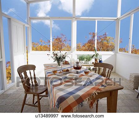 Stock Photo - Table with cakes and tea in conservatory. Fotosearch