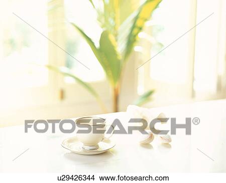 Picture - Tea cup on table next to nuts. Fotosearch
