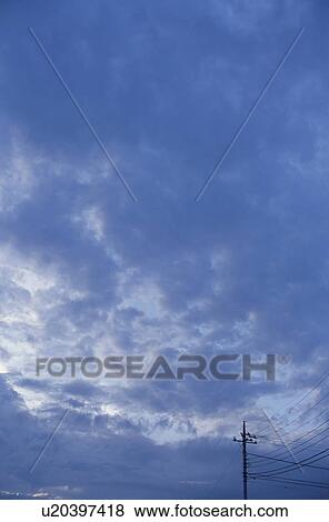 Stock Photo - Telephone pole under a blue cloud-filled sky. Fotosearch