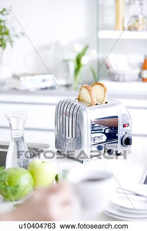 Stock Image - Toaster on kitchen counter and hand holding coffee cup. Fotosearch