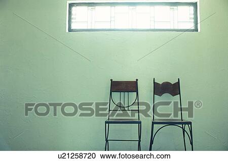 Stock Image - Two chairs below window in aqua room. Fotosearch