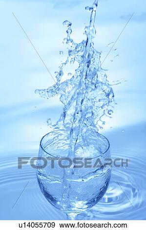Stock Photo - Water pouring into glass, blue background. Fotosearch